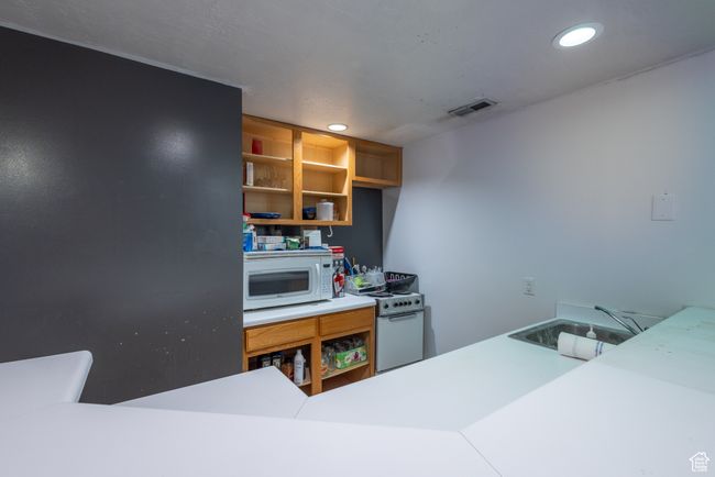 Kitchen featuring recessed lighting, white appliances, open shelves, visible vents, and a sink | Image 19