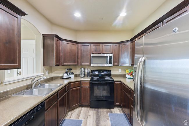 Kitchen with a sink, light countertops, black appliances, recessed lighting, and light wood finished floors | Image 4