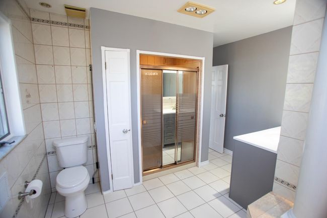 Bathroom featuring toilet, vanity, tile patterned floors, and tile walls | Image 16