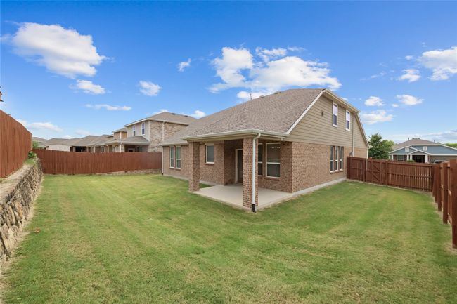 Rear view of property with brick siding, a fenced backyard, a patio area, and a shingled roof | Image 36