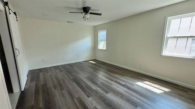 Unfurnished bedroom featuring a barn door, dark wood-style floors, and ceiling fan | Image 20