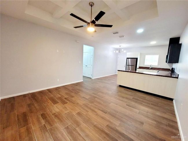 Unfurnished living room with light wood-style floors, baseboards, and coffered ceiling | Image 9