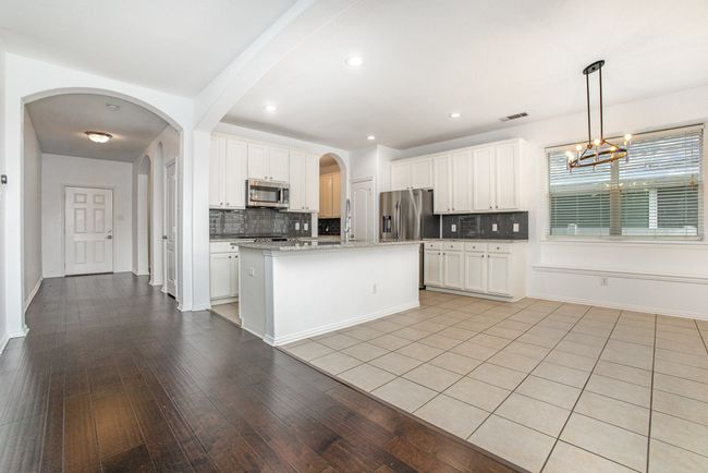 Kitchen featuring white cabinetry, appliances with stainless steel finishes, backsplash, and tile floor. | Image 8