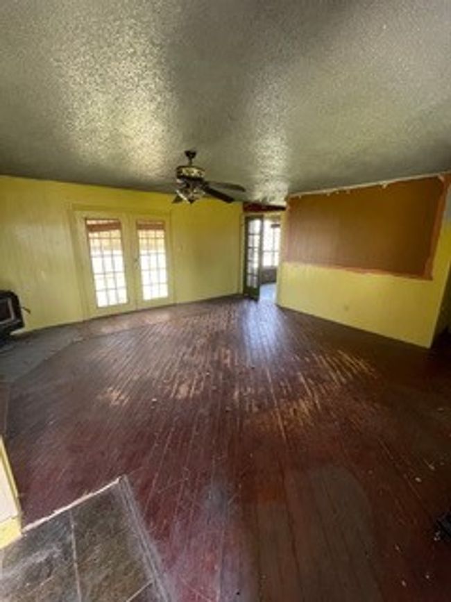 Unfurnished living room featuring a ceiling fan, a textured ceiling, a wood stove, and hardwood / wood-style floors | Image 19