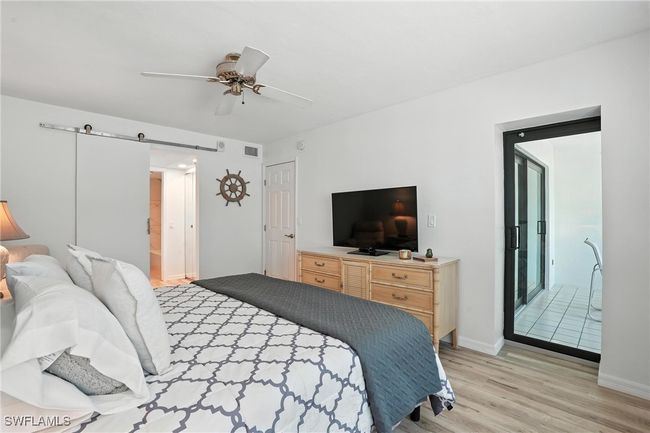 Bedroom featuring light wood finished floors, a barn door, and ceiling fan | Image 26