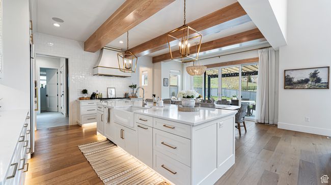 Kitchen with light wood finished floors, beam ceiling, a sink, and a notable chandelier | Image 21
