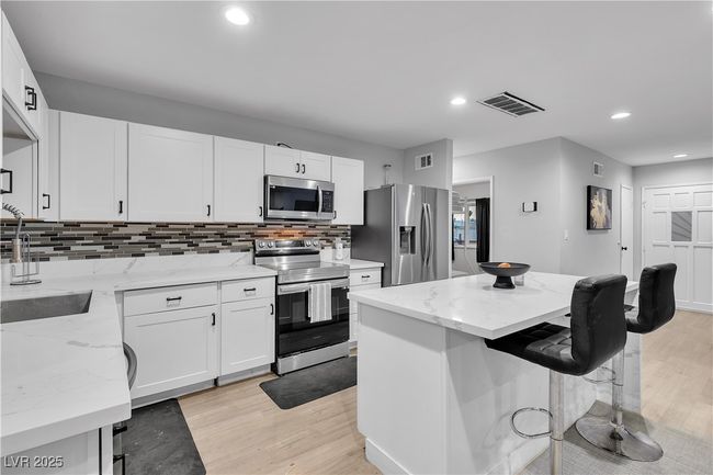 Kitchen with a breakfast bar, visible vents, appliances with stainless steel finishes, and decorative​​‌​​​​‌​​‌‌​‌‌​​​‌‌​​‌‌​‌​​​​​‌ backsplash | Image 12