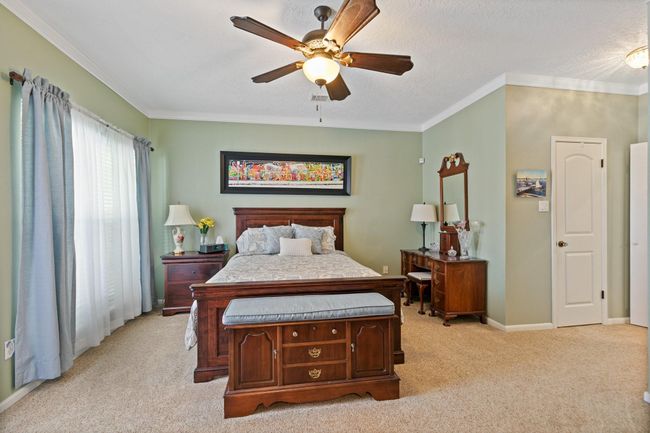 Spacious primary bedroom featuring a serene color palette for a relaxing retreat. The room offers ample natural light, a ceiling fan, and thoughtful layout with convenient access to the ensuite bathroom for comfort and privacy. | Image 16
