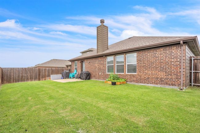 Back of property featuring brick siding, a fenced backyard, a chimney, a patio area, and a shingled roof | Image 26