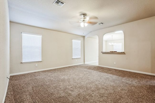 Carpeted spare room featuring ceiling fan with notable chandelier | Image 4