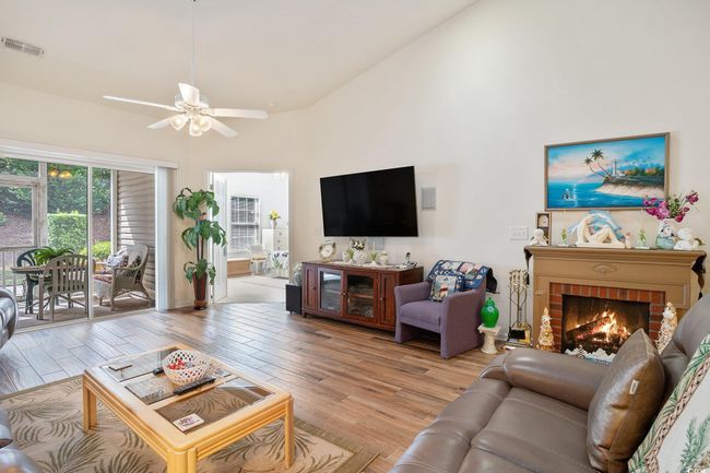 Living room featuring light wood-style floors, a fireplace, ceiling fan, and high vaulted ceiling | Image 13