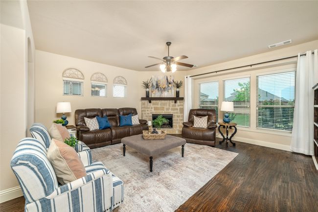 Living area with baseboards, dark wood-type flooring, a ceiling fan, and a stone fireplace | Image 12