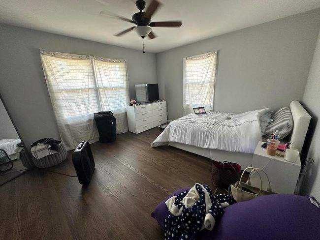 Bedroom featuring a ceiling fan, wood finished floors, and multiple windows | Image 8