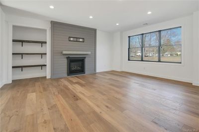 Living room featuring light wood-type flooring and a large fireplace. "Please note that the photos provided are from a previous build and serve as examples only. The final finishes and features may vary based on selections made during the construction process." | Image 3