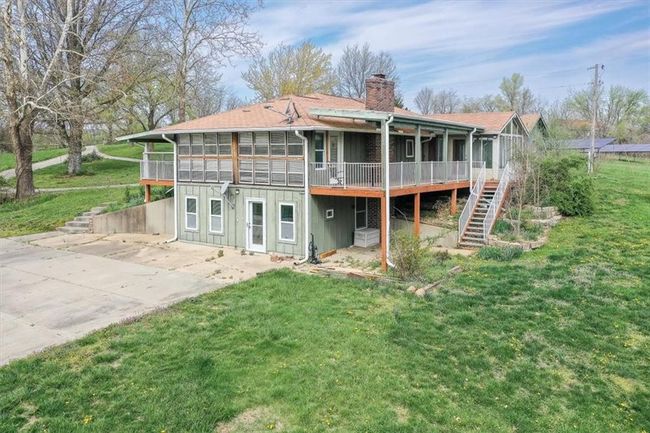 Rear view of property featuring a chimney, stairs, a yard, a patio, and a deck | Image 5