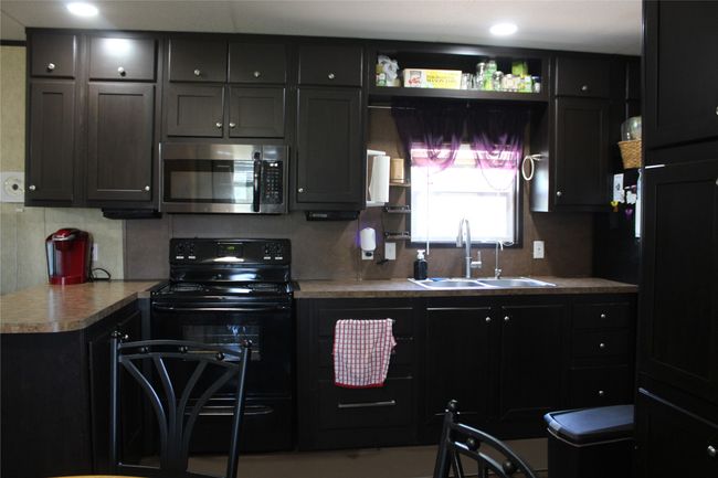 Kitchen with stainless steel microwave, black stove, a sink, and tasteful backsplash | Image 30