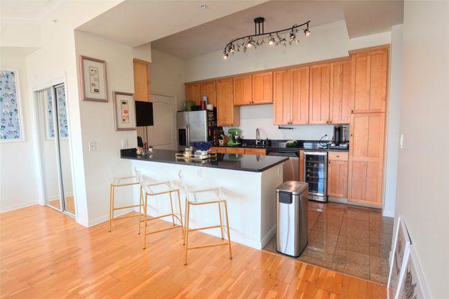 Kitchen featuring a breakfast bar area, dark countertops, appliances with stainless steel finishes, wine cooler, and a peninsula | Image 31