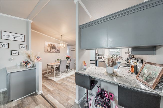 Kitchen featuring ornamental molding, light wood finished floors, light stone counters, a breakfast bar, and a peninsula | Image 10