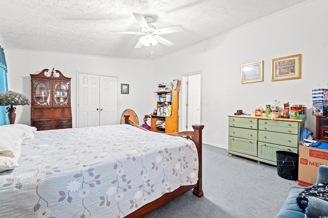 Carpeted bedroom featuring a textured ceiling, a ceiling fan, and a closet | Image 13