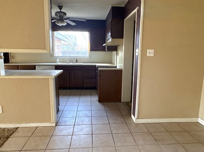 Kitchen with light tile patterned flooring, light countertops, a ceiling fan, and a sink | Image 4