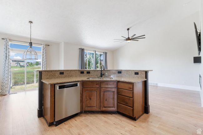 Kitchen with stainless steel dishwasher, light wood-type flooring, ceiling fan, light stone countertops, and lofted ceiling | Image 16