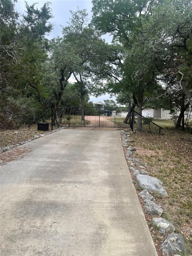 View of concrete driveway featuring a gate and a gated entry | Image 6