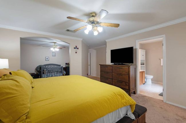 Bedroom with crown molding, light carpet, ceiling fan, and ensuite bath | Image 14