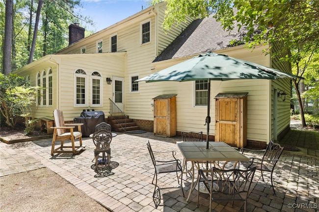 Rear view of house featuring entry steps, a chimney, a patio, and outdoor dining area | Image 40