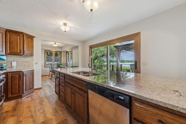 Bright kitchen and dining flow seamlessly into the outdoor deck area, offering an ideal space for entertaining with lake views. | Image 8