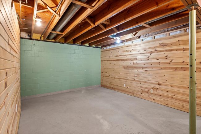 Unfinished basement space featuring wood-paneled walls. | Image 12