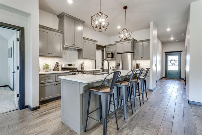 Kitchen featuring stainless steel appliances, a sink, light wood-type flooring, gray cabinetry, and a notable chandelier | Image 37
