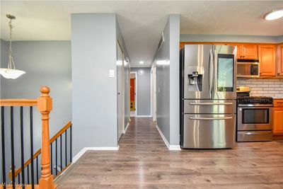 Kitchen featuring tasteful backsplash, light hardwood / wood-style floors, hanging light fixtures, and appliances with stainless steel finishes | Image 2