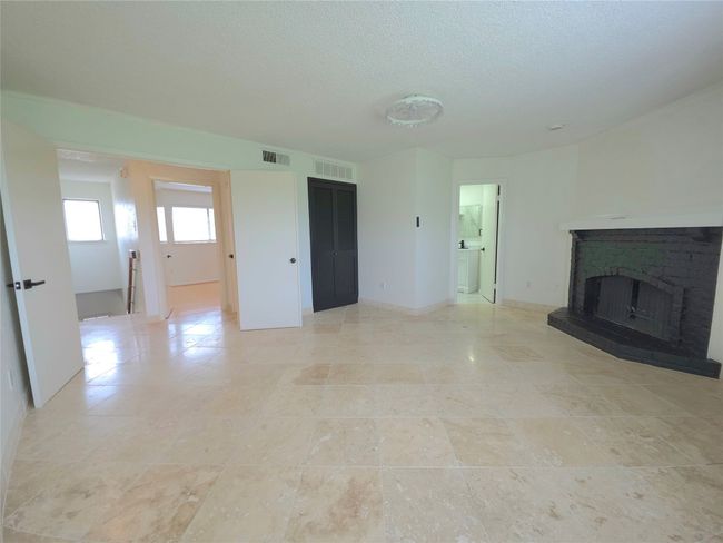 Unfurnished living room featuring a brick fireplace, light tile patterned flooring, and a textured ceiling | Image 12