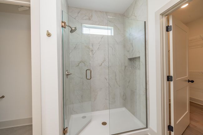 Frameless Glass Shower Door with Full Wall Tiles champagne bronze fixtures, transom window, and niche | Image 20