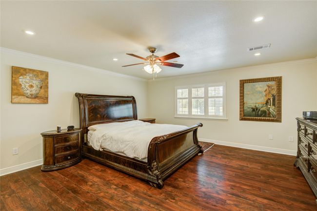 The primary bedroom featureswarm wood floors, multipleclosets, a serene pool view, anda private en-suite bathroom forultimate comfort and privacy. | Image 19