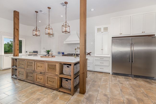 Kitchen featuring stainless steel built in fridge, premium range hood, light countertops, white cabinetry, and glass insert cabinets | Image 11