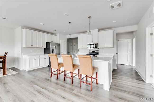 Kitchen featuring appliances with stainless steel finishes, light wood-type flooring, light countertops, and a kitchen bar | Image 10