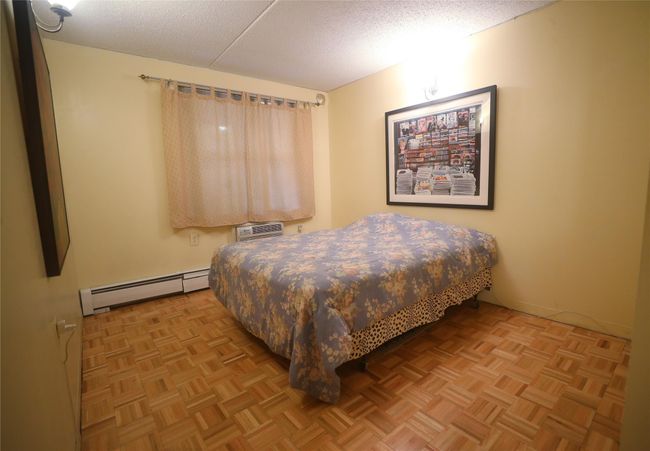Bedroom with a baseboard heating unit, a textured ceiling, and a wall mounted AC | Image 24