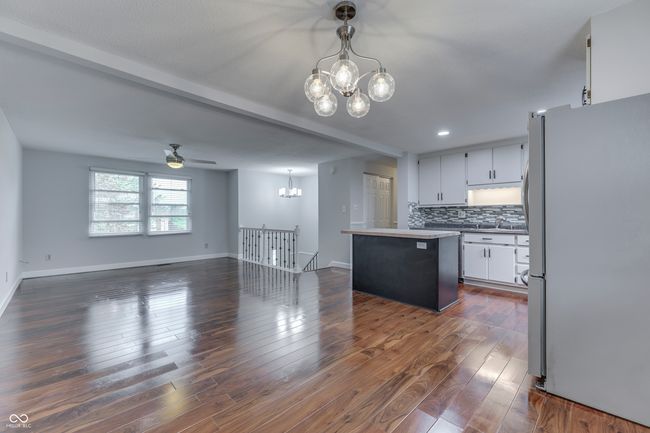 kitchen featuring decorative backsplash, white cabinetry, freestanding refrigerator, open floor plan, and dark wood finished floors | Image 11