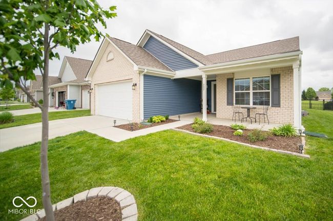 ranch-style home with an attached garage, brick siding, covered porch, and a front yard | Image 5