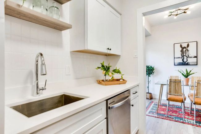 Kitchen featuring white cabinetry, decorative backsplash, stainless steel dishwasher, sink, and light wood-type flooring | Image 7