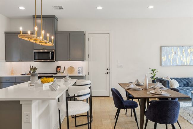 Kitchen featuring a breakfast bar, visible vents, gray cabinets, tasteful backsplash, and stainless steel microwave | Image 9