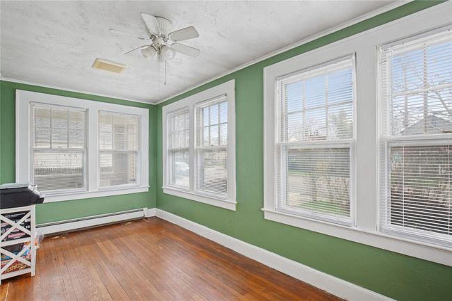 Sunroom / solarium featuring baseboards, crown molding, visible vents, wood-type flooring, and a baseboard radiator | Image 15