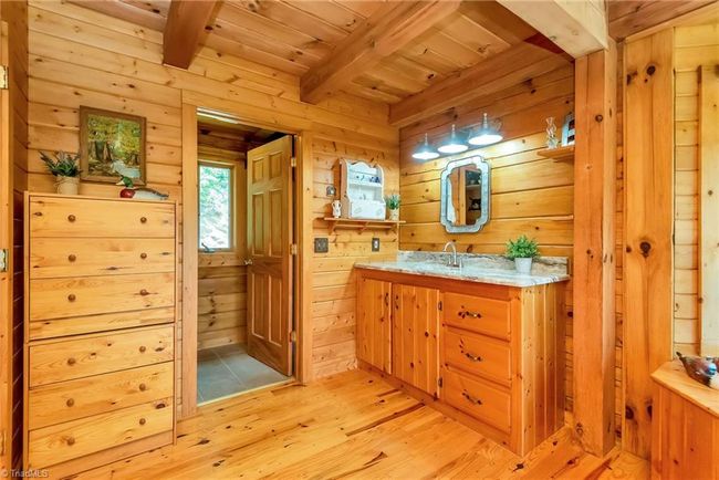 The upper level of the log cabin boasts a cozy loft area leading to two bedrooms, along with one full bath and one half bath, offering a charming and functional layout perfect for family living or guest accommodations. | Image 30