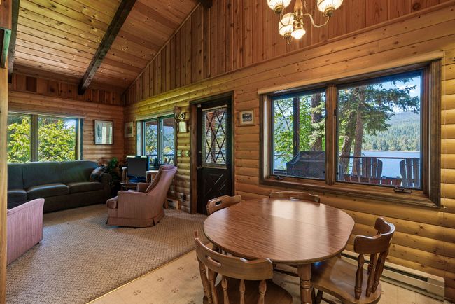 Dining area with log walls, a chandelier, high vaulted ceiling, a wooden ceiling with exposed beams, and a baseboard heating unit | Image 17