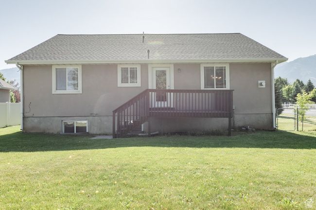 Rear view of house with stucco siding, a shingled roof, and a mountain view | Image 25