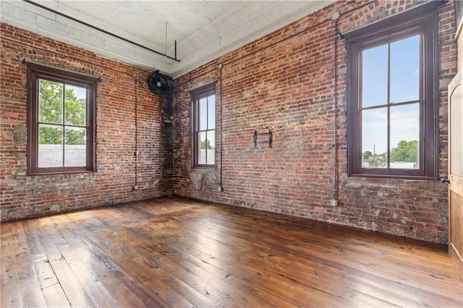 Empty room featuring hardwood / wood-style flooring, healthy amount of natural light, and brick wall | Image 11