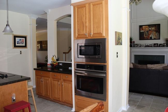 Kitchen featuring appliances with stainless steel finishes, dark countertops, light tile patterned flooring, decorative columns, and a fireplace | Image 11