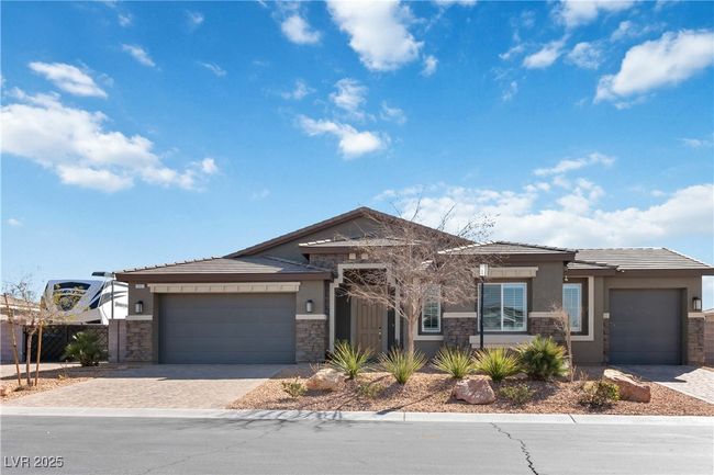 View of front facade featuring an attached garage, fence, stone siding, driveway, and stucco siding | Image 7