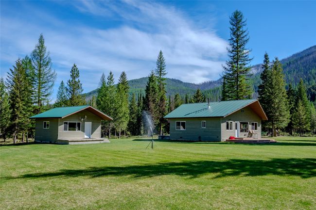 Rear view of house featuring a forest view, a lawn, a mountain view, and metal roof | Image 38
